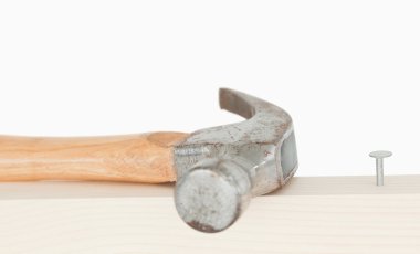 A hammer and a drived nail on a wooden board clipart