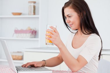 Close up of a woman using her laptop and drinking juice clipart