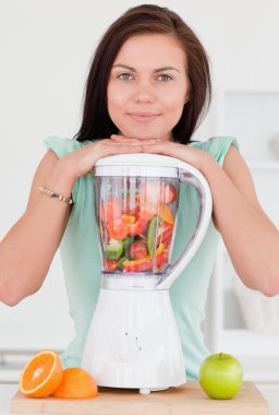 Smiling dark-haired woman posing with a blender clipart