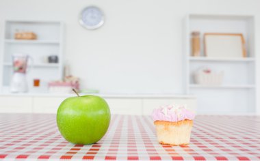 An apple and a cupcake on a tablecloth clipart