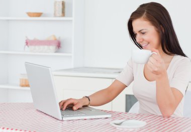 Charming woman using her laptop and having a tea clipart