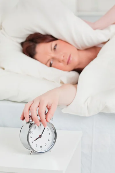 Cute red-haired woman waking up thanks to an alarm clock — Stock Photo, Image