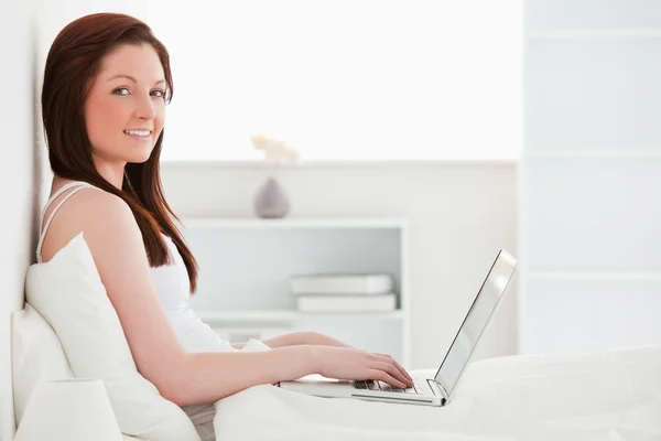 Piękna rudowłosa kobieta relaksując się przy jej laptop podczas sitti — Zdjęcie stockowe