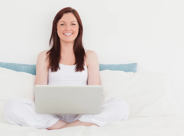 Piękna, rudowłosa kobieta relaksując się przy jej laptopa siedząc — Zdjęcie stockowe