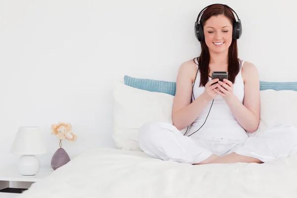 Attraktiva rödhårig kvinna lyssna på musik med hennes headphon — Stockfoto
