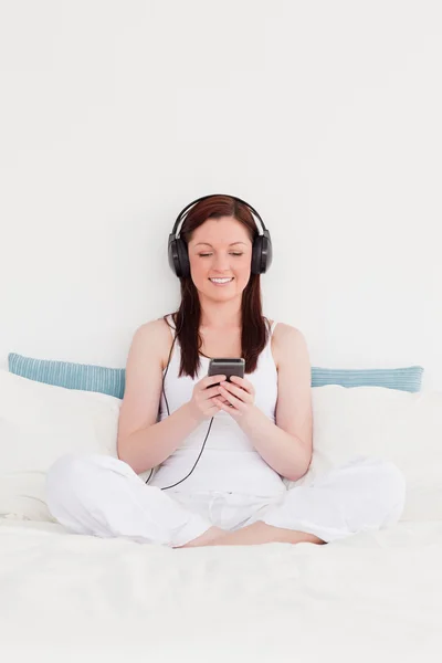 Snygg rödhårig kvinna lyssna på musik med hennes headph — Stockfoto