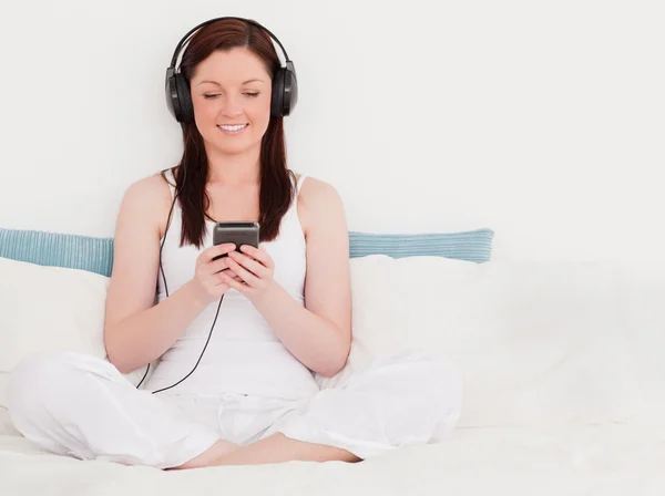Uroczy rudowłosa kobieta słuchanie muzyki z jej słuchawki — Zdjęcie stockowe