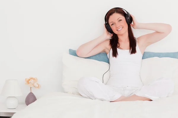 Söt rödhårig kvinna lyssna på musik med hennes hörlurar w — Stockfoto