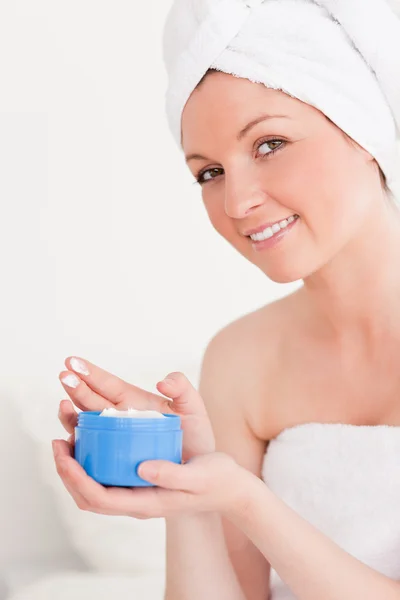 Aantrekkelijke jonge vrouw dragen een handdoek met behulp van huid crème — Stockfoto