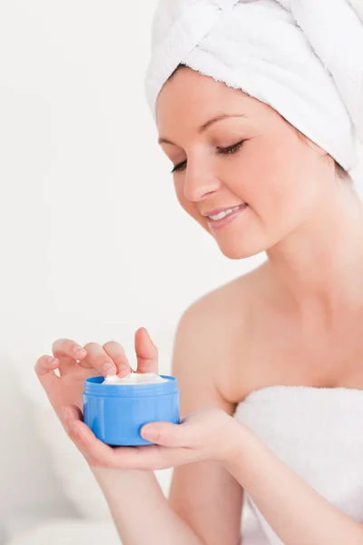 Красивая молодая женщина, завернутая в полотенце с помощью крема для кожи — стоковое фото