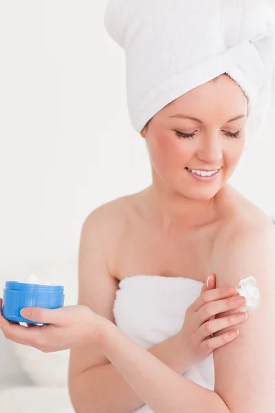 Mignon jeune femme portant une serviette à l'aide de crème pour la peau — Photo