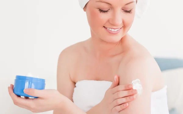 Pretty young woman wearing a towel using skin cream — Stock Photo, Image
