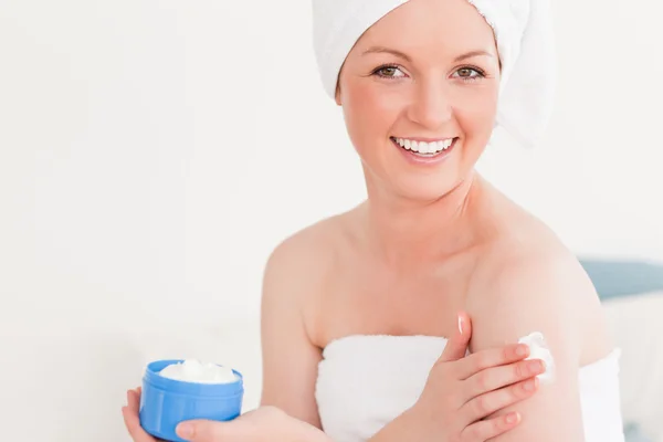Belle jeune femme portant une serviette avec de la crème pour la peau — Photo