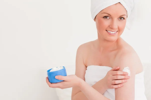 Knappe jonge vrouw dragen een handdoek met behulp van huid crème — Stockfoto