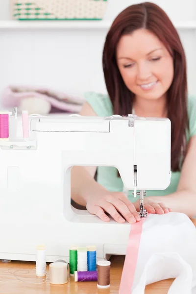 Gorgeous red-haired woman using a sewing machine in the living r — Stock Photo, Image