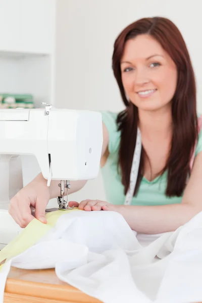 Good looking red-haired female using a sewing machine in the liv — Stock Photo, Image