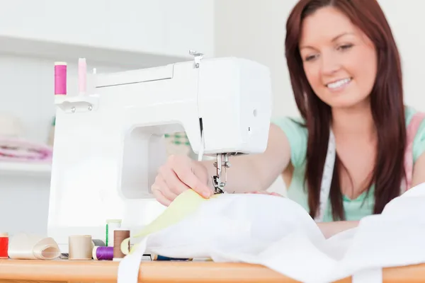 Attractive red-haired female sewing in the living room — Stock Photo, Image