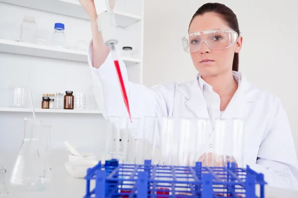 Beautiful female biologist holding a manual pipette with sample — Stock Photo, Image