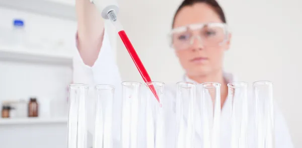 Beautiful red-haired scientist filling up a test tube — Stock Photo, Image