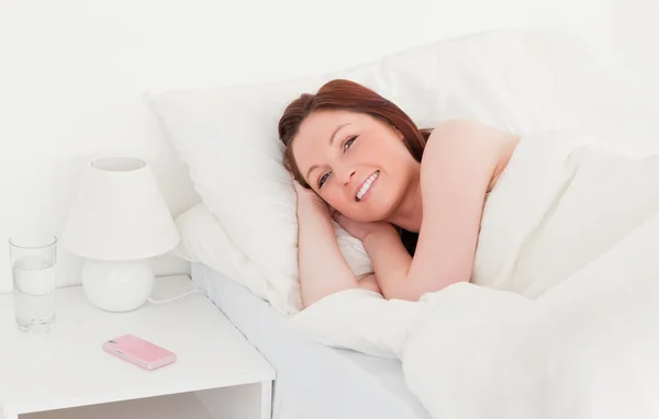 Привлекательная рыжая женщина расслабляется, лежа на кровати — стоковое фото