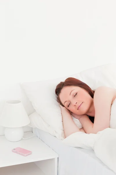 Hermosa mujer pelirroja relajándose mientras está acostada en su cama —  Fotos de Stock