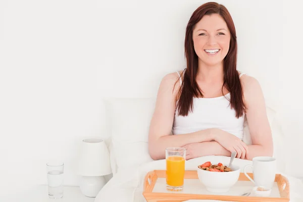 Beautiful red-haired woman having her breakfast while sitting on — Stock Photo, Image