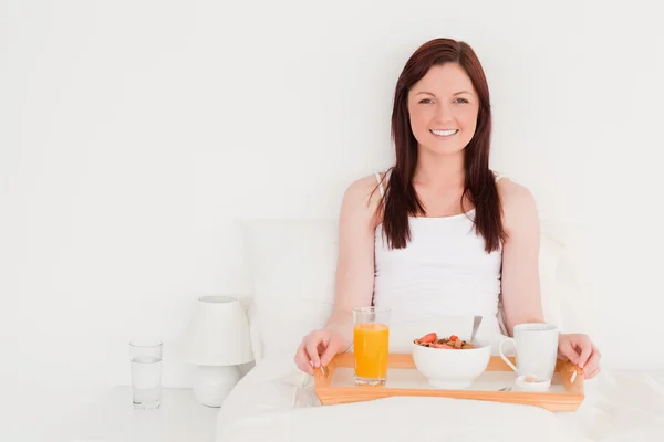 Atrakcyjny rudowłosa kobieta o jej śniadanie podczas posiedzenia o — Zdjęcie stockowe
