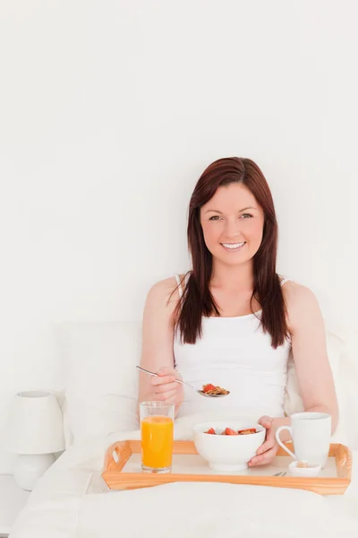 Mujer pelirroja de buen aspecto desayunando mientras está sentada —  Fotos de Stock