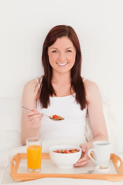 Gorgeous red-haired woman having her breakfast while sitting on — Stock Photo, Image