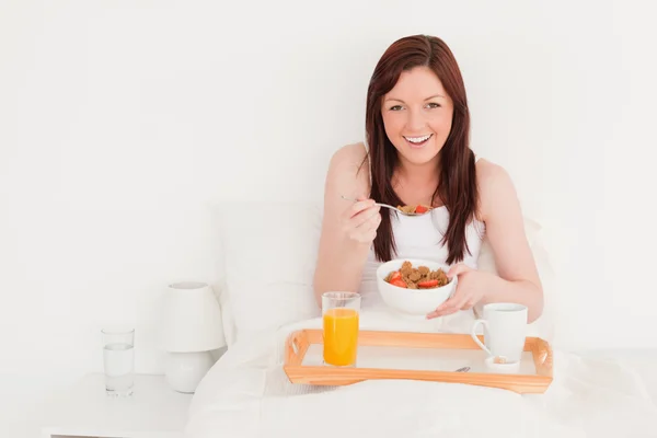 Pretty red-haired female having her breakfast while sitting on h — Stock Photo, Image