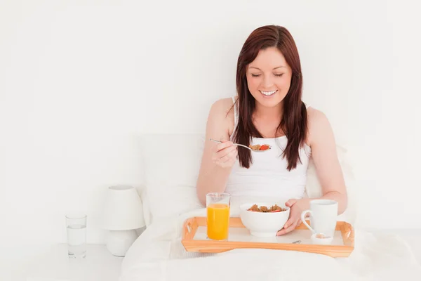 Beautiful red-haired female having her breakfast while sitting o — Stock Photo, Image