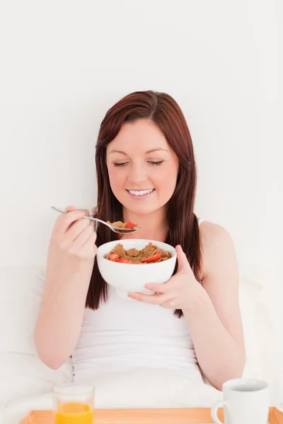Atraente fêmea ruiva tomando seu café da manhã enquanto sentada — Fotografia de Stock