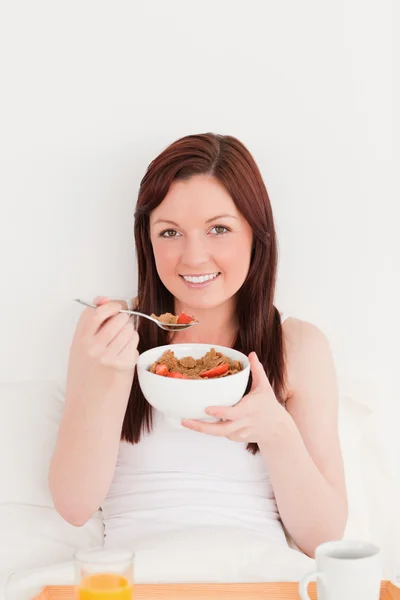 Gorgeous red-haired female having her breakfast while sitting on — Stock Photo, Image
