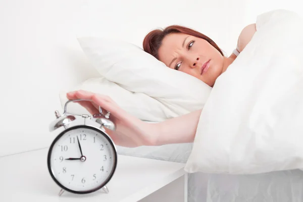 Όμορφη κοκκινομάλλης γυναίκα ξυπνάει χάρη σε ένα ρολόι συναγερμών — Φωτογραφία Αρχείου