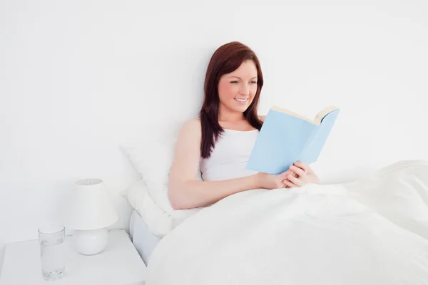 Güzel kızıl saçlı kadın onun b üzerinde otururken bir kitap okuma — Stok fotoğraf