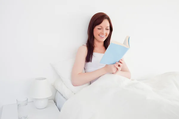 Good looking red-haired woman reading a book while sitting on he — Stock Photo, Image