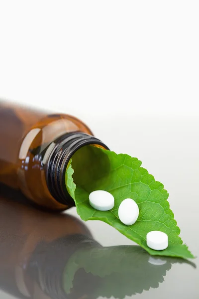 Leaf and pills in a small bottle — Stock Photo, Image