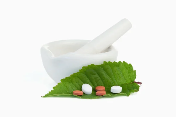 Mortar and pestle with pills on a leaf — Stock Photo, Image
