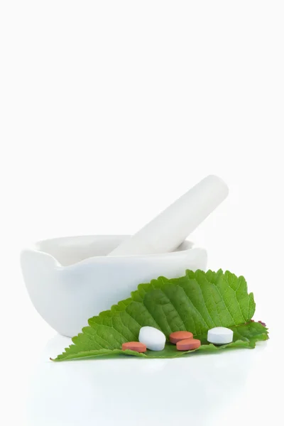 Argamassa e pilão com pílulas em uma folha — Fotografia de Stock