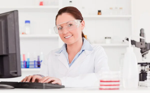 Young scientist typing a report with her computer — Stock Photo, Image