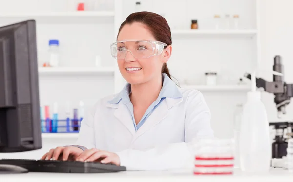 Cute scientist typing a report with her computer — Stock Photo, Image