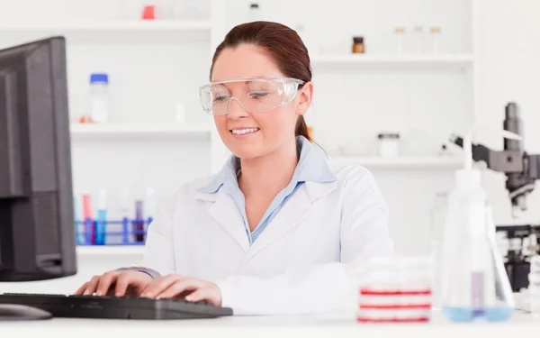 Beautiful scientist typing a report with her computer — Stock Photo, Image