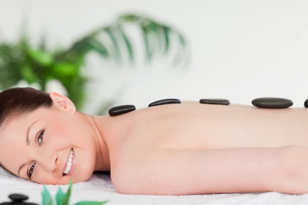 Sorridente bella donna avendo un massaggio di pietra — Foto Stock