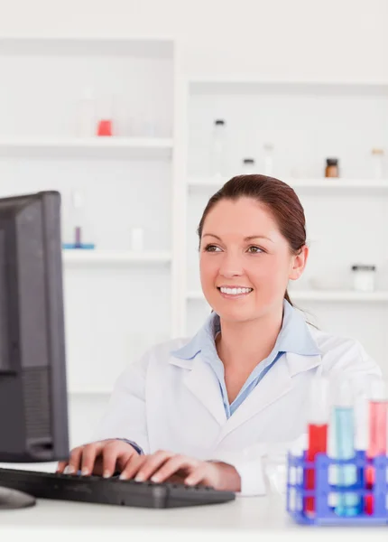 Smiling scientist typing a report with her computer — Stock Photo, Image