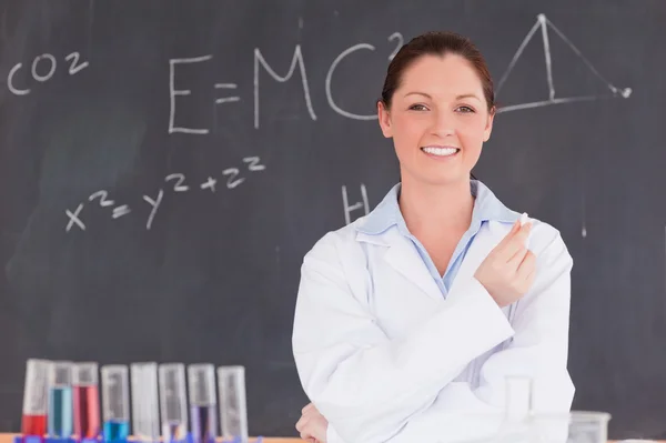 Young scientist holding a piece of chalk while standing in front — Stock Photo, Image