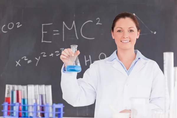 Cientista bonito segurando um recipiente cheio com um líquido azul — Fotografia de Stock