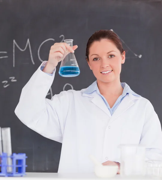 Πανέμορφη επιστήμονας δείχνει ένα δοχείο που γεμίζουν επάνω με ένα μπλε li — Φωτογραφία Αρχείου