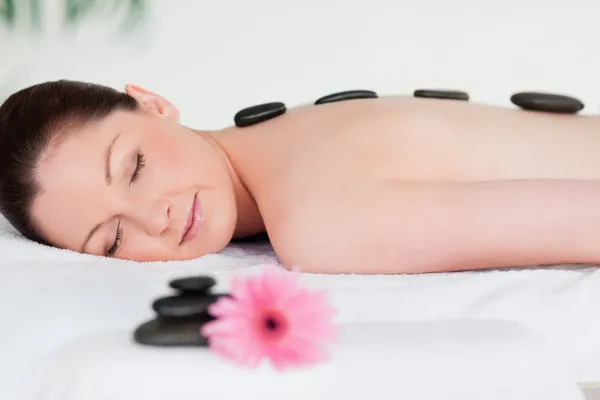 Giovane donna con un massaggio di pietre nere — Foto Stock