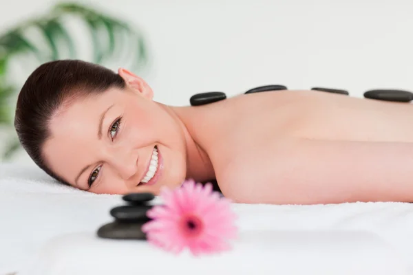 Šťastná mladá žena s růžová gerbera a masážní kameny — Stock fotografie