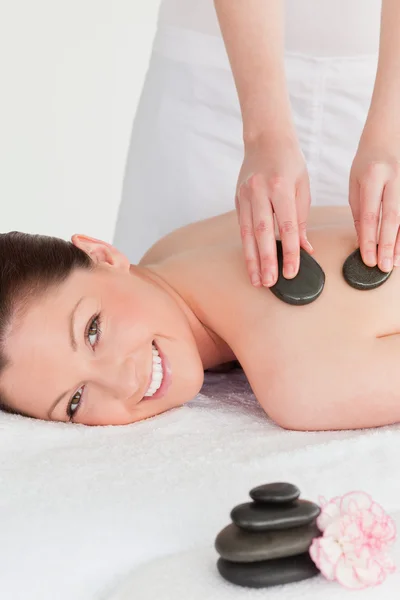 Smiling young redhead woman having a hot stone massage — Stock Photo, Image